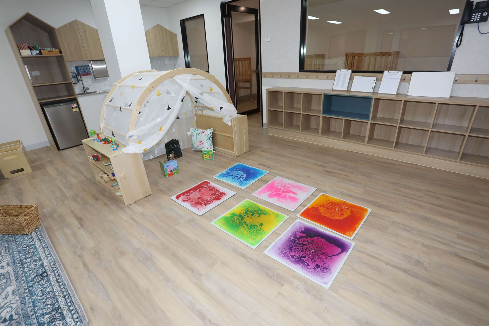 A baby play space with a timber climbing arch and colourful sensory floor tiles