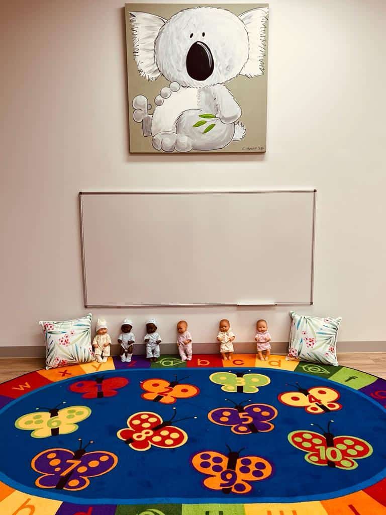 A group-time rug with a koala artwork on the wall above it