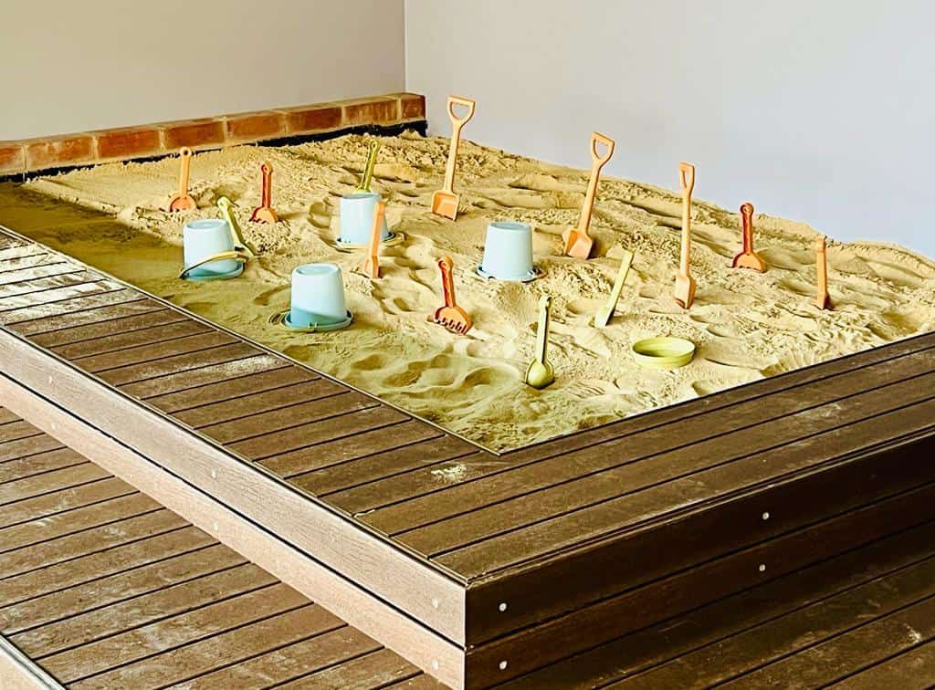 A timber-edged sandpit with spades and buckets