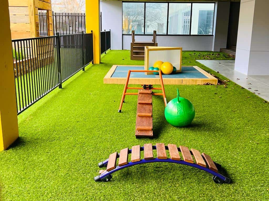 A balance beam, rocker and ball on soft green turf
